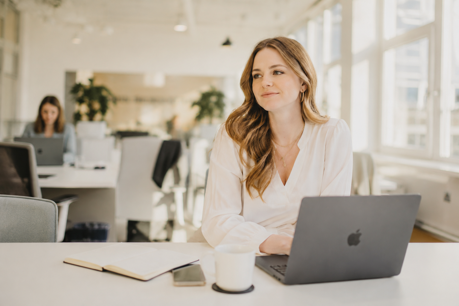 Frau sitzt an einem hellen Arbeitsplatz mit Laptop und Notizbuch – symbolisiert den Aufbau eines Corporate Influencer Programms im modernen Unternehmenskontext.